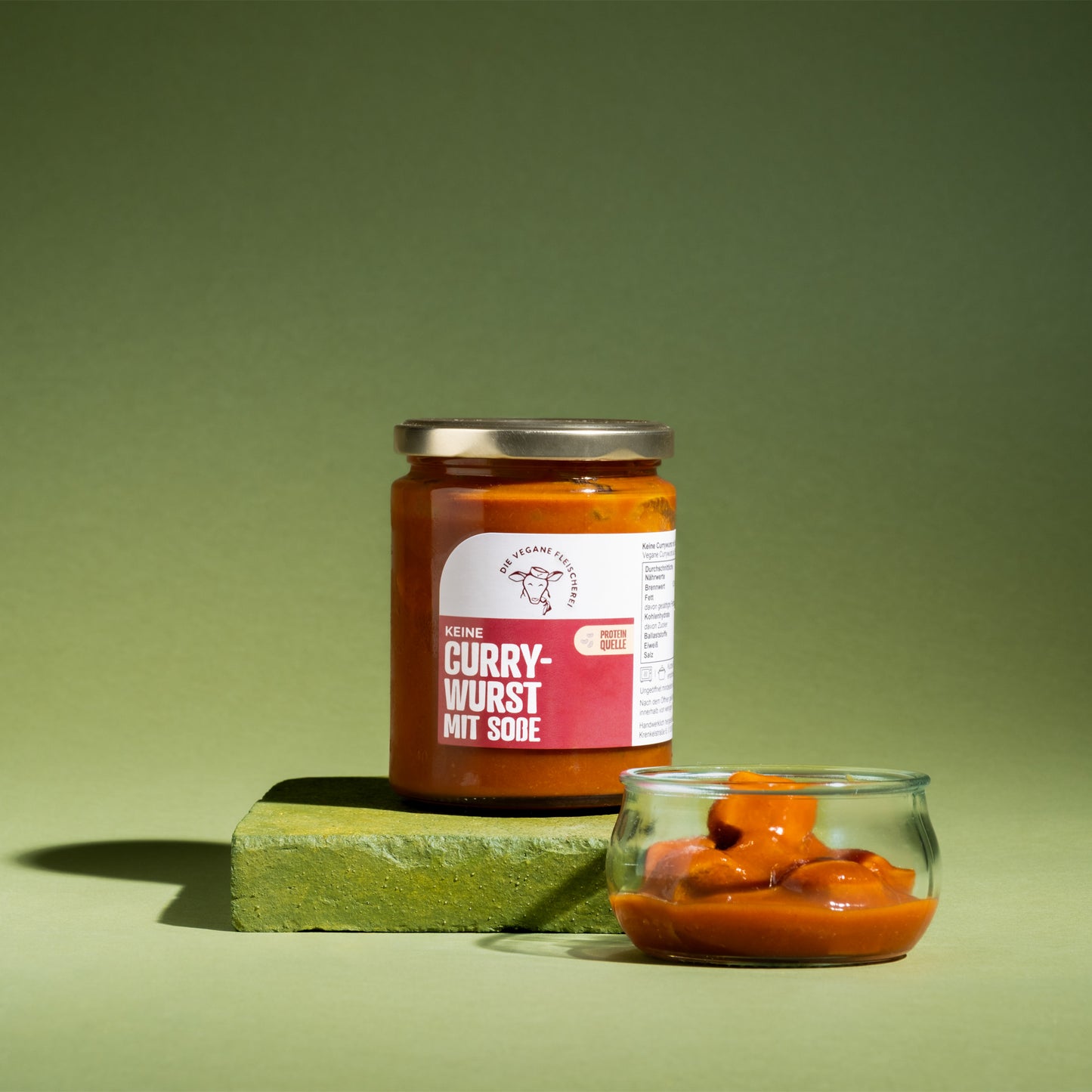 Vegane Currywurst mit Soße in Glas, proteinreich, pflanzlich, orangefarben angerichtet