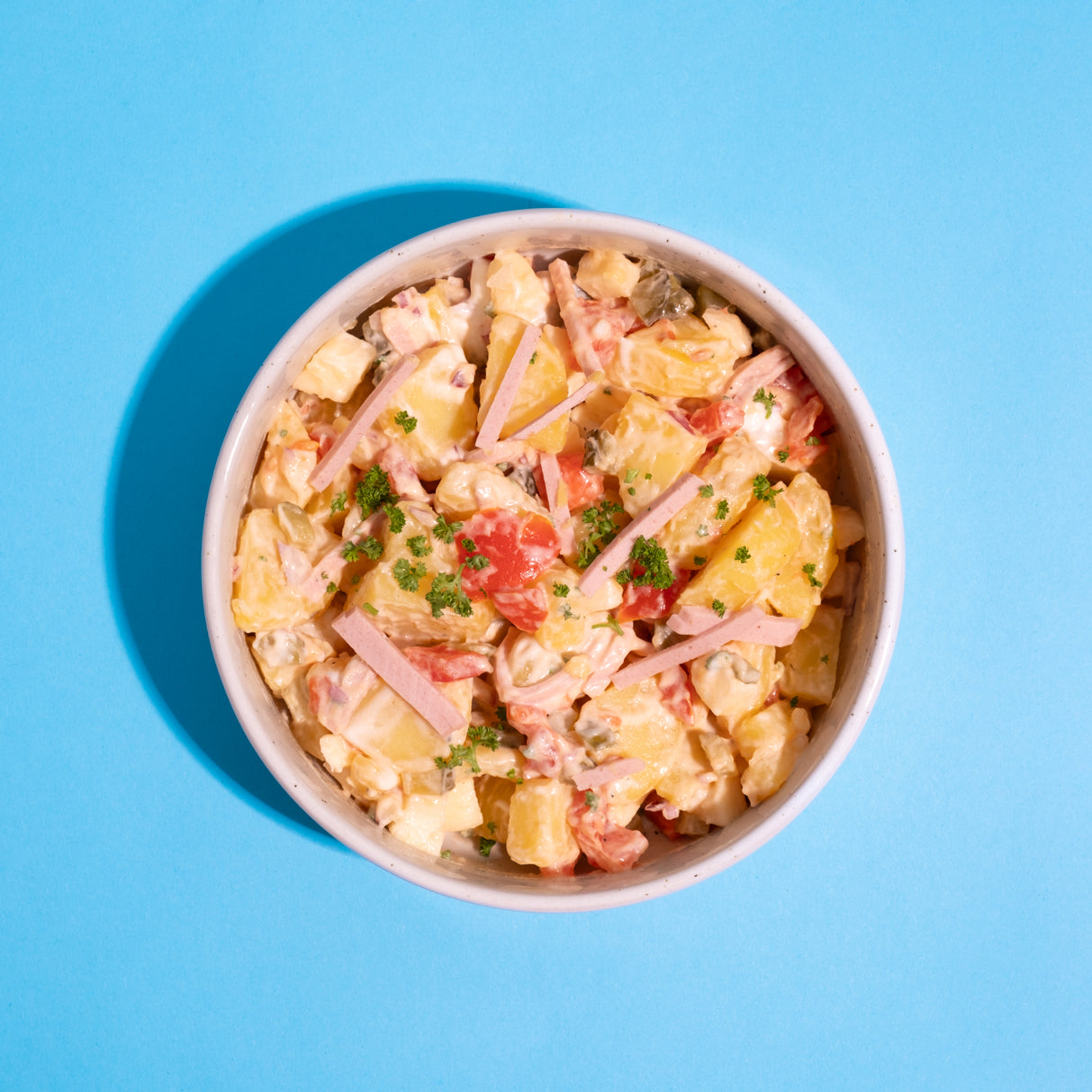 Veganer Fleischwurstsalat auf blauem Hintergrund.