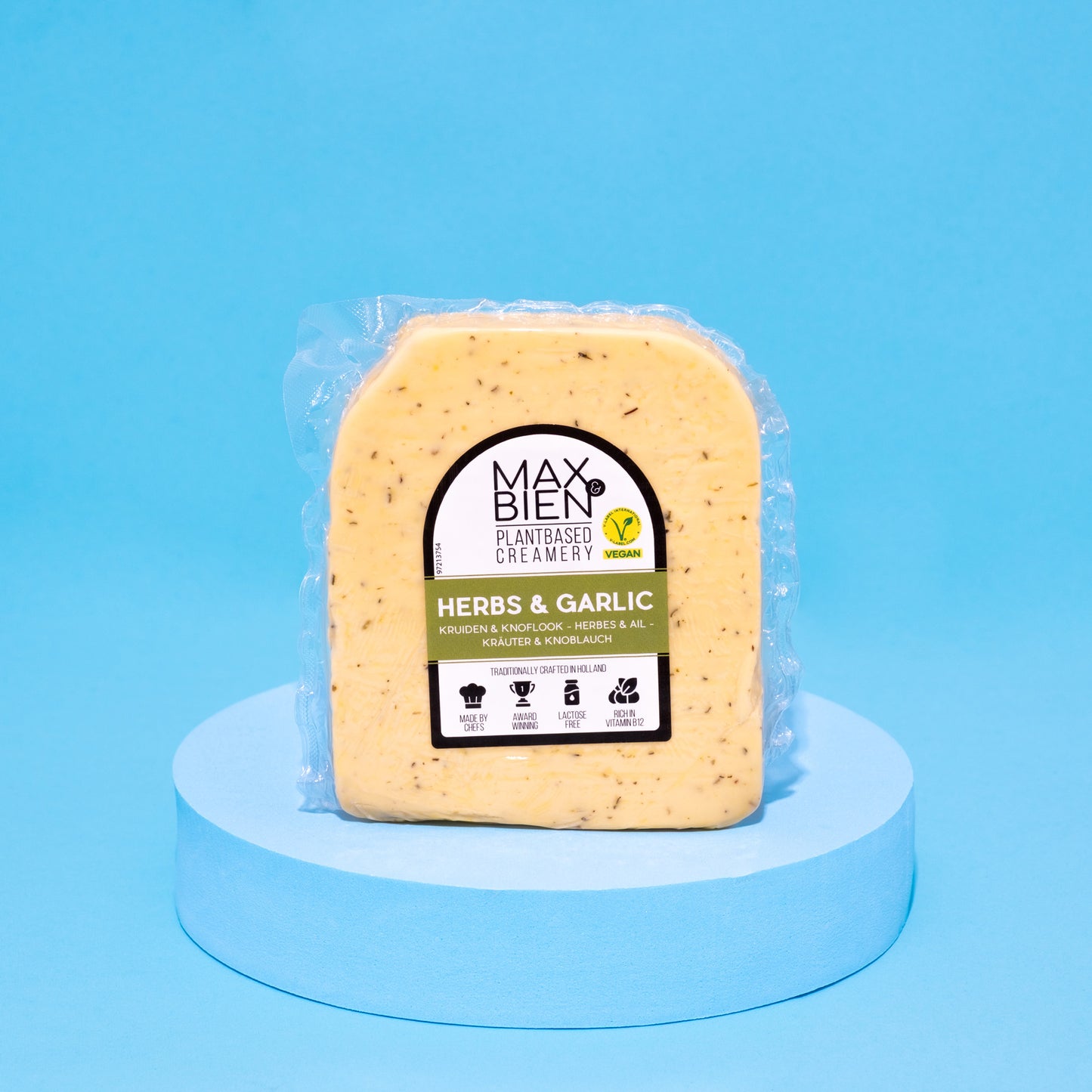 Veganer Kräuter-Knoblauch-Käse auf blauem Podest vor blauem Hintergrund.