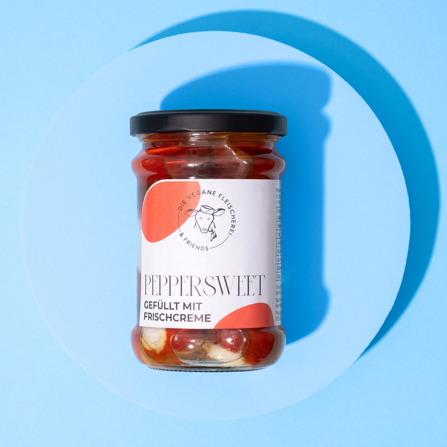 Glas mit Peppersweet gefüllten frischen Chilis in roter Marinade, weißes Etikett mit schwarzer Schrift und orangenen.