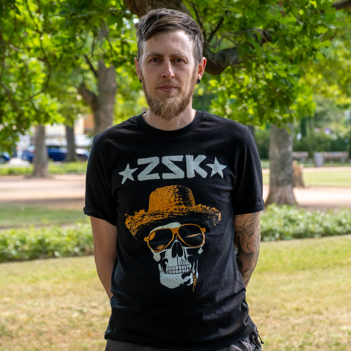 Andreas aus der Produktion, im Park in schwarzem Band-T-Shirt