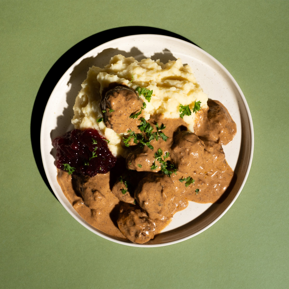 „Keine Köttbullar“ in Rahmsoße mit Kartoffelpüree, Preiselbeeren und Petersilie auf einem Teller, von oben