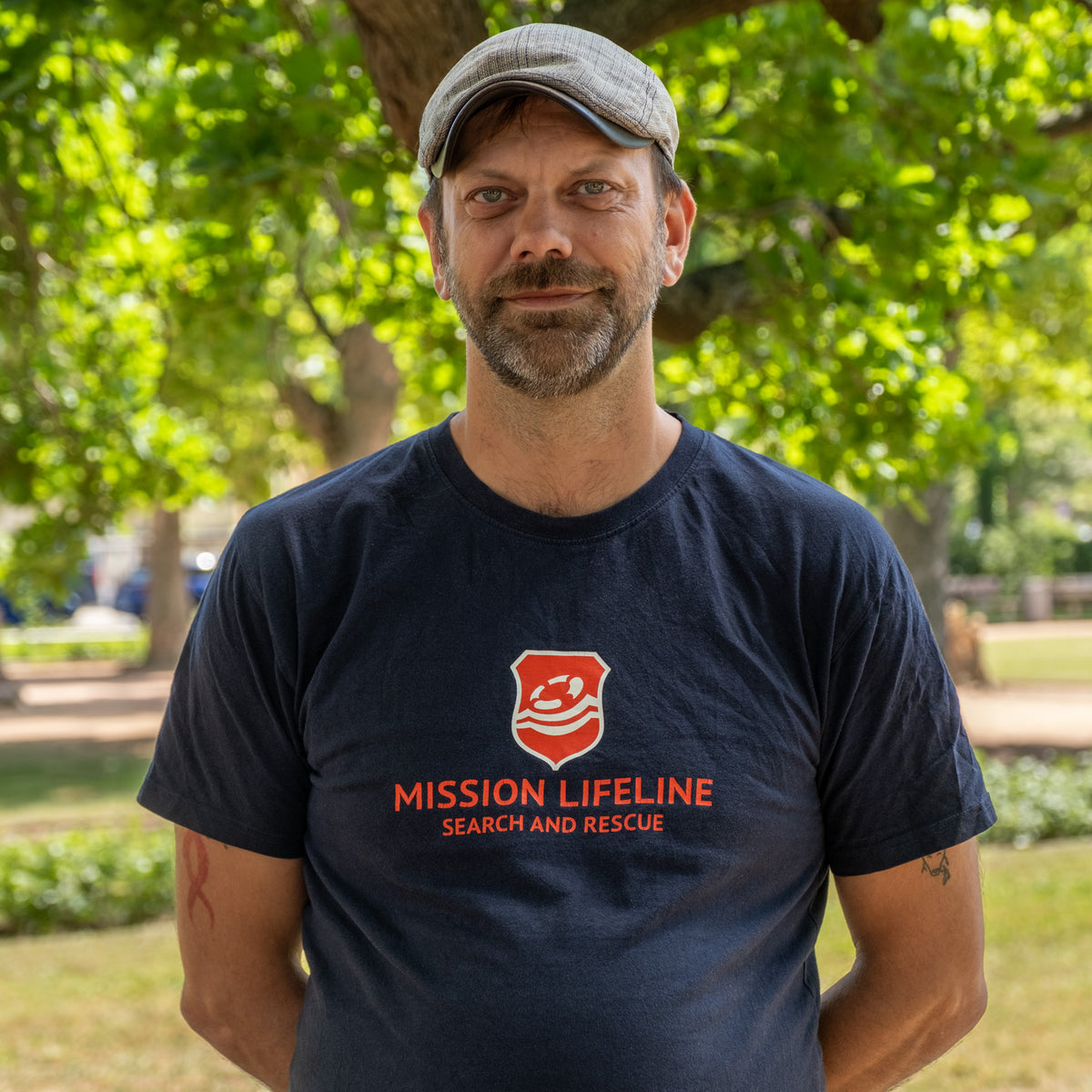 Quis aus der Produktion, im Park mit Schiebermütze und dunkelblauem T-Shirt