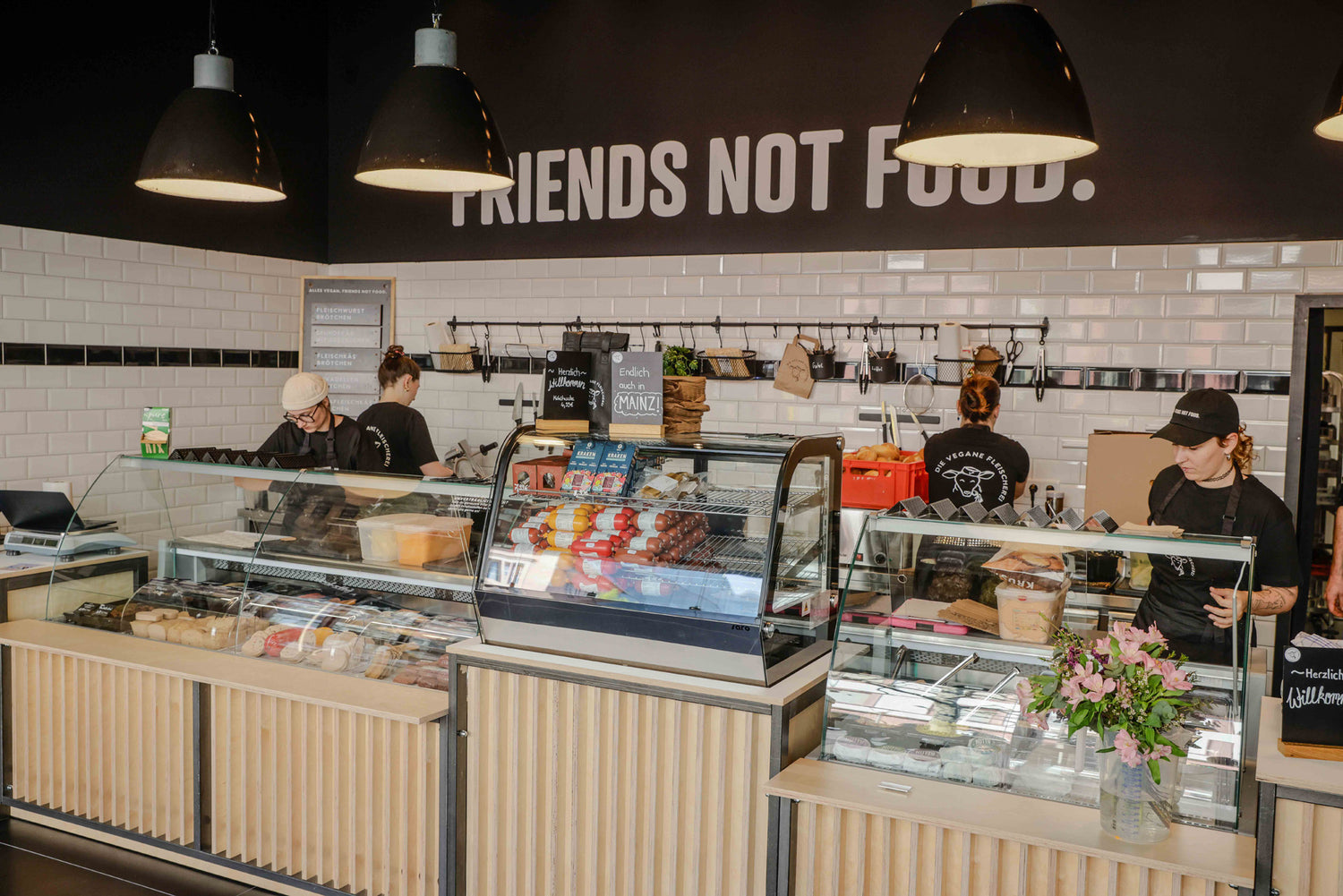 Innenansicht der Veganen Fleischerei Mainz mit Verkaufstheke, veganen Produkten und Mitarbeitenden hinter dem Tresen - Bildmaterial von Vegane Fleischerei