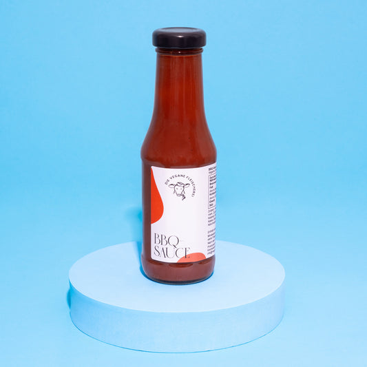 Flasche BBQ-Sauce auf blauem Podest vor blauem Hintergrund.