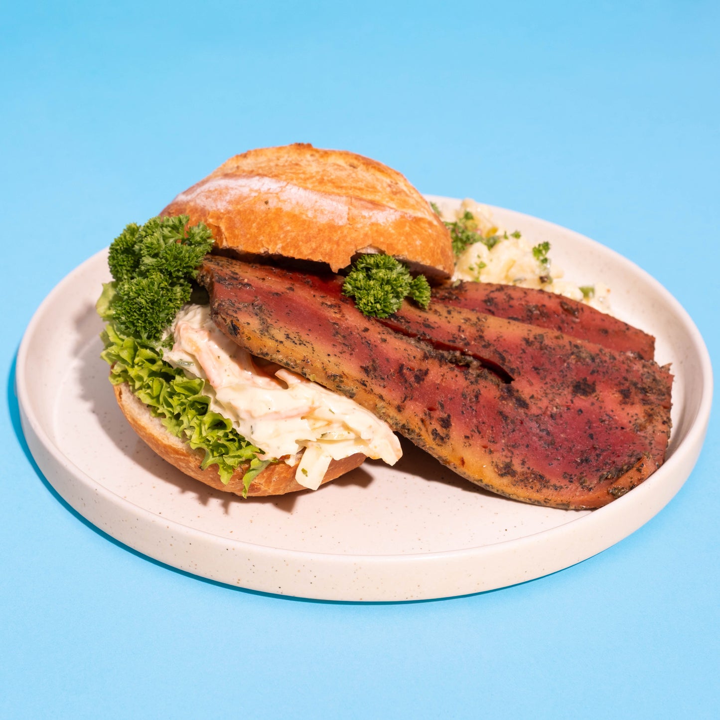 Veganer Grillbacon mit Kräutermarinade im Brötchen mit Kartoffelsalat.