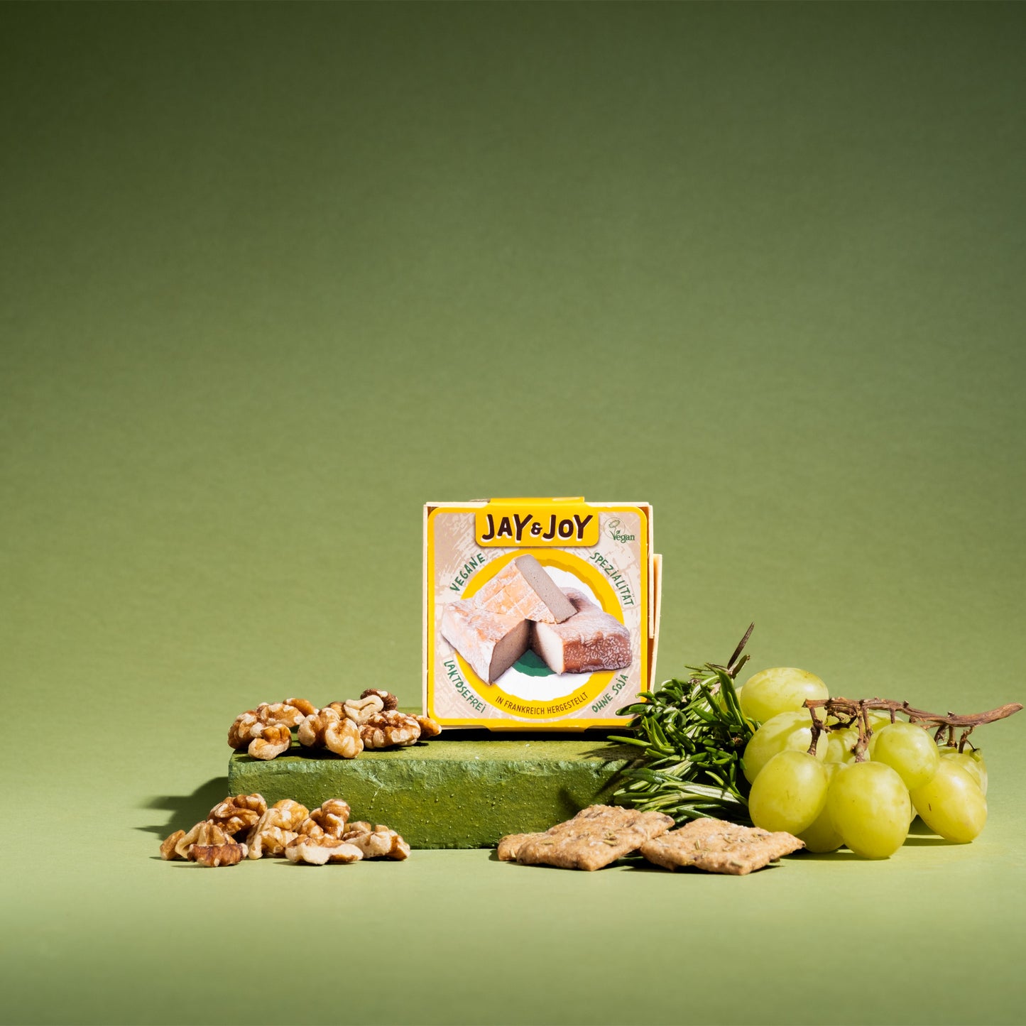 Vegane Spezialität von Jay&Joy mit Walnüssen, Trauben und Kräckern auf grünem Podest