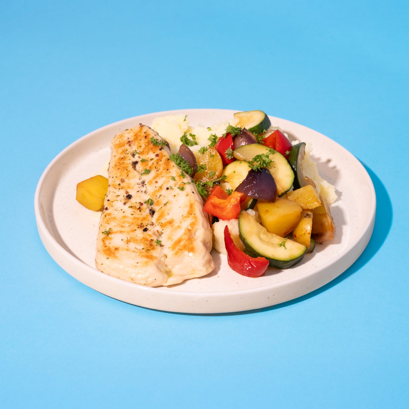 Kein-Fischfilet auf weißem Teller mit Gemüse.