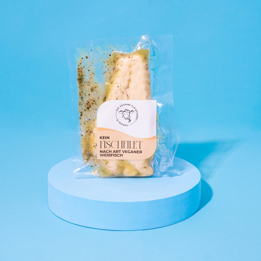 Verpacktes Kein-Fischfilet auf blauem Podest vor blauem Hintergrund.