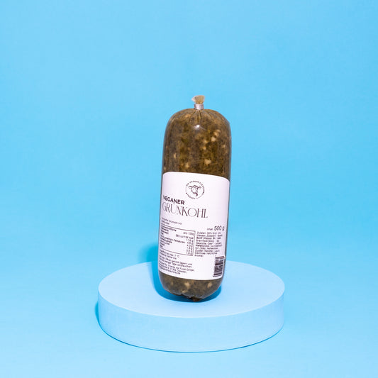 Veganer Grünkohl in Verpackung auf blauem Podest vor blauem Hintergrund.