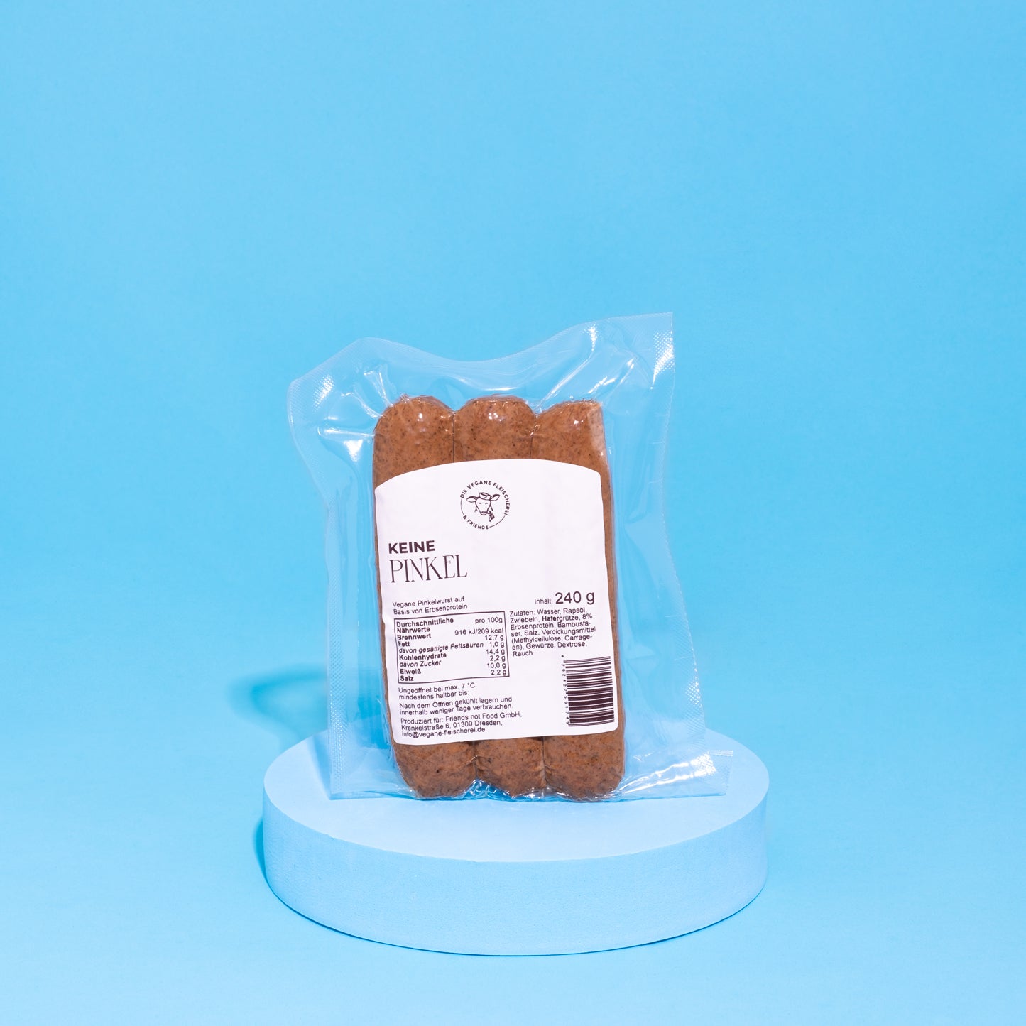 Vegane Pinkelwurst in Verpackung auf blauem Podest vor blauem Hintergrund. 