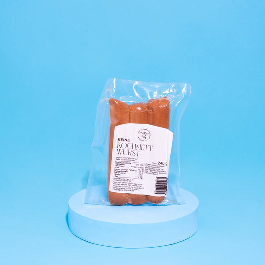 Vegane Fleischwurst auf blauen Podest vor blauem Hintergrund.