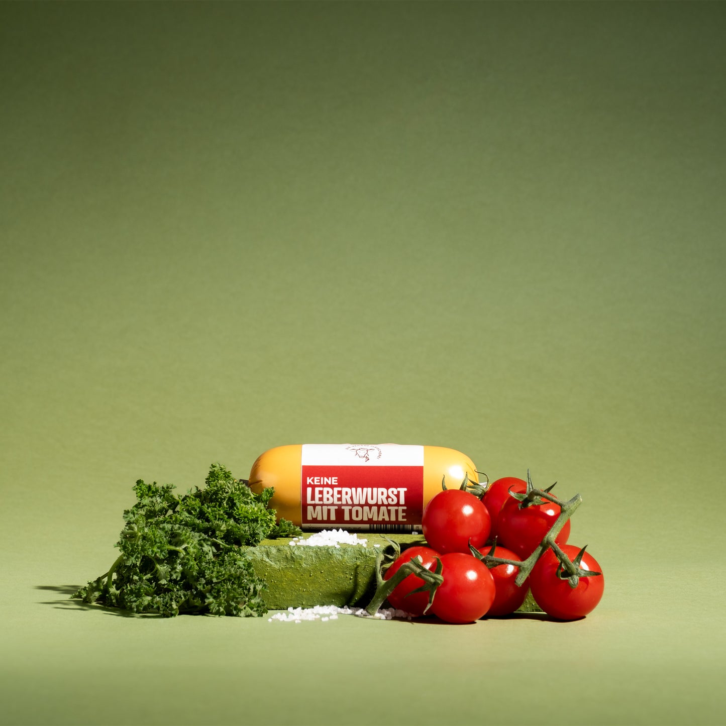 Vegane Leberwurst mit Tomate, proteinreich, 100% pflanzlich, serviert mit frischen Tomaten und Petersilie auf grünem Hintergrund