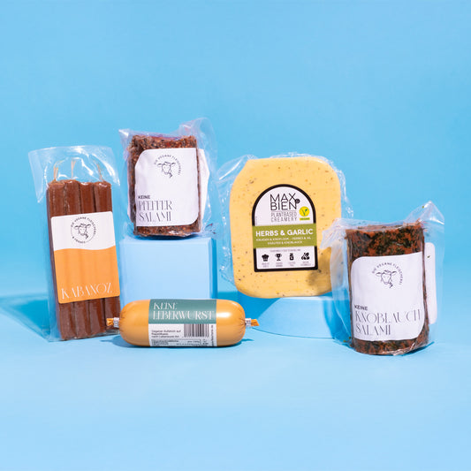 Produkt-Bundle „Brotzeit“ mit verschiedenen veganen Wurst- und Käsealternativen auf hellblauem Hintergrund.