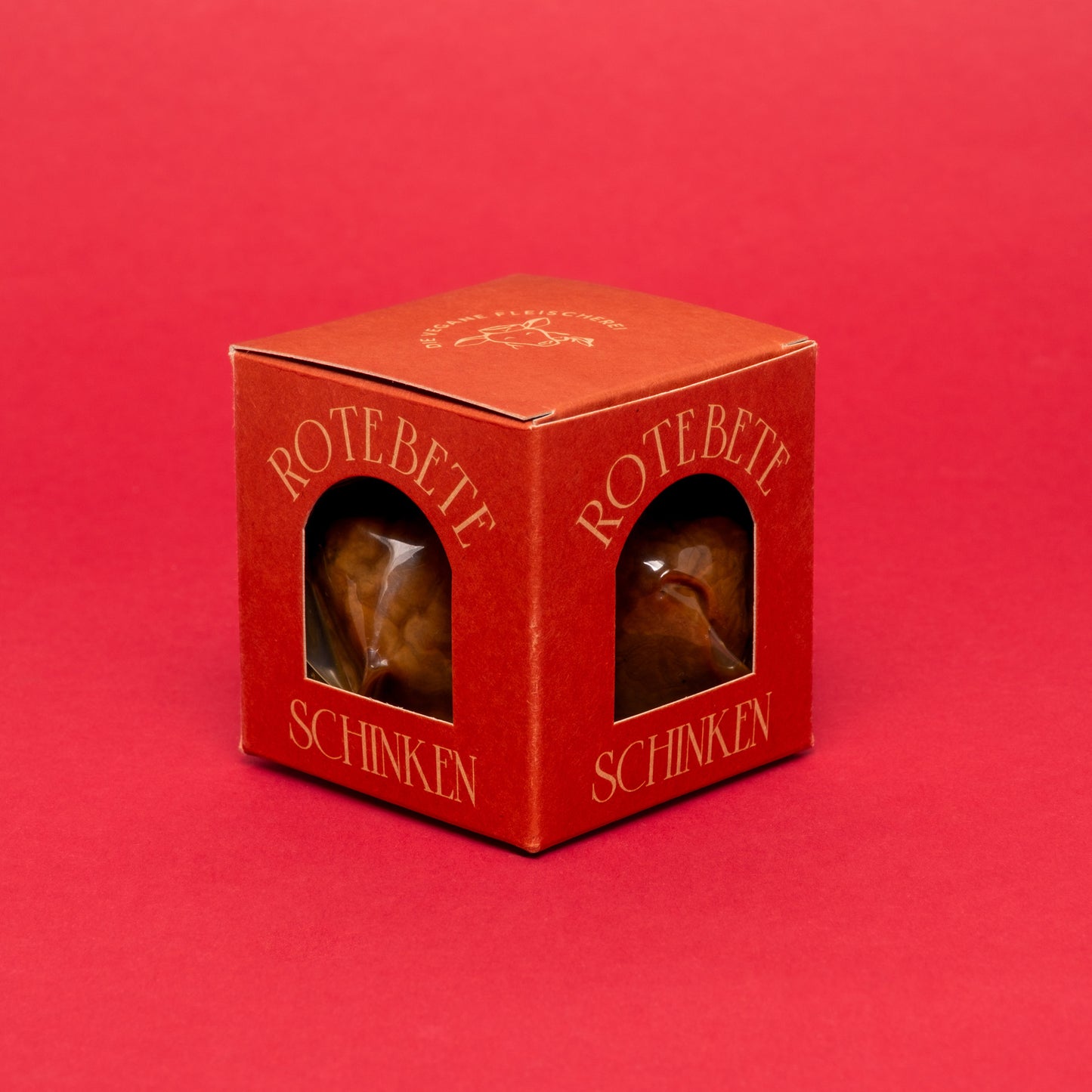 Rote Box mit veganem Rote-Bete-Schinken auf rotem Hintergrund.
