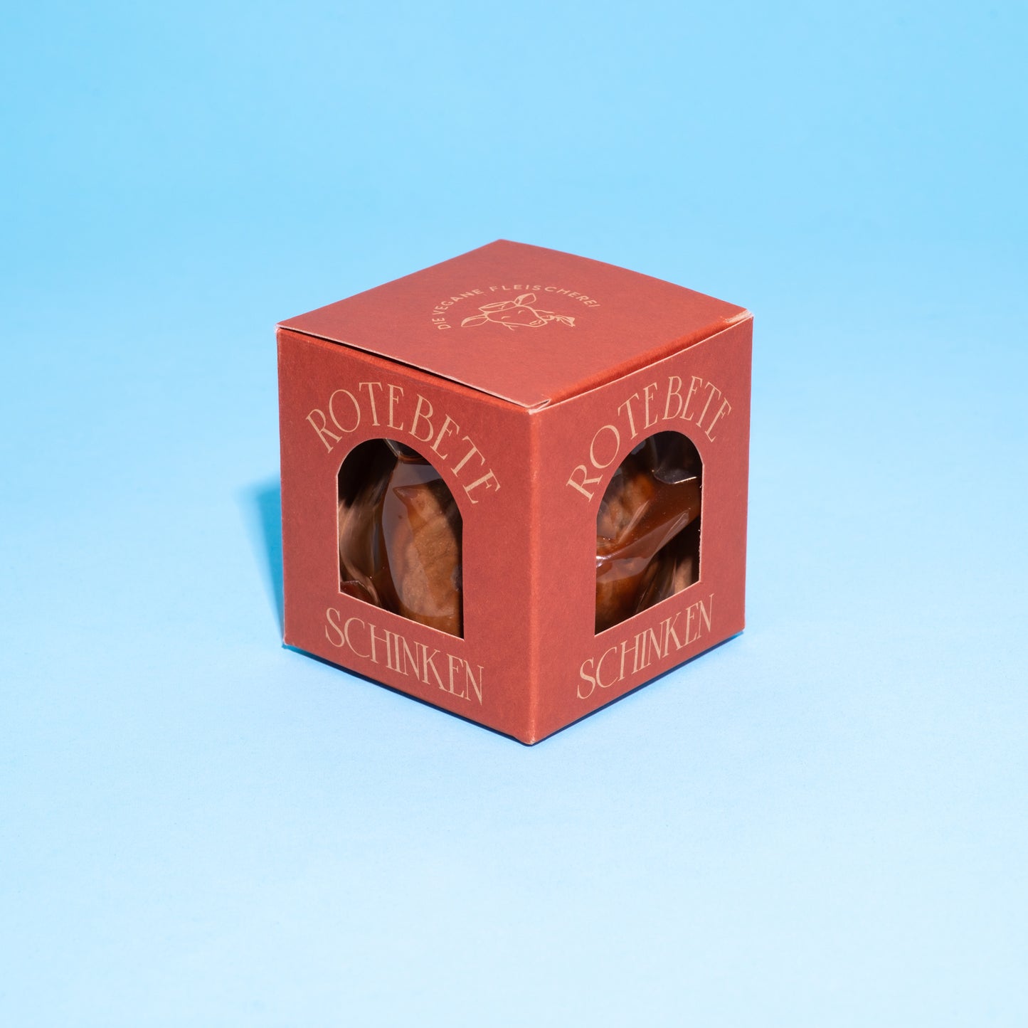 Rote Box mit veganem Rote-Bete-Schinken auf blauen Hintergrund.